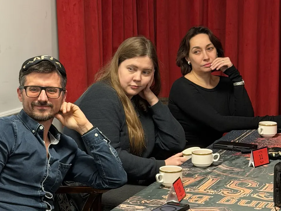 Guests at the game table in front of red curtains