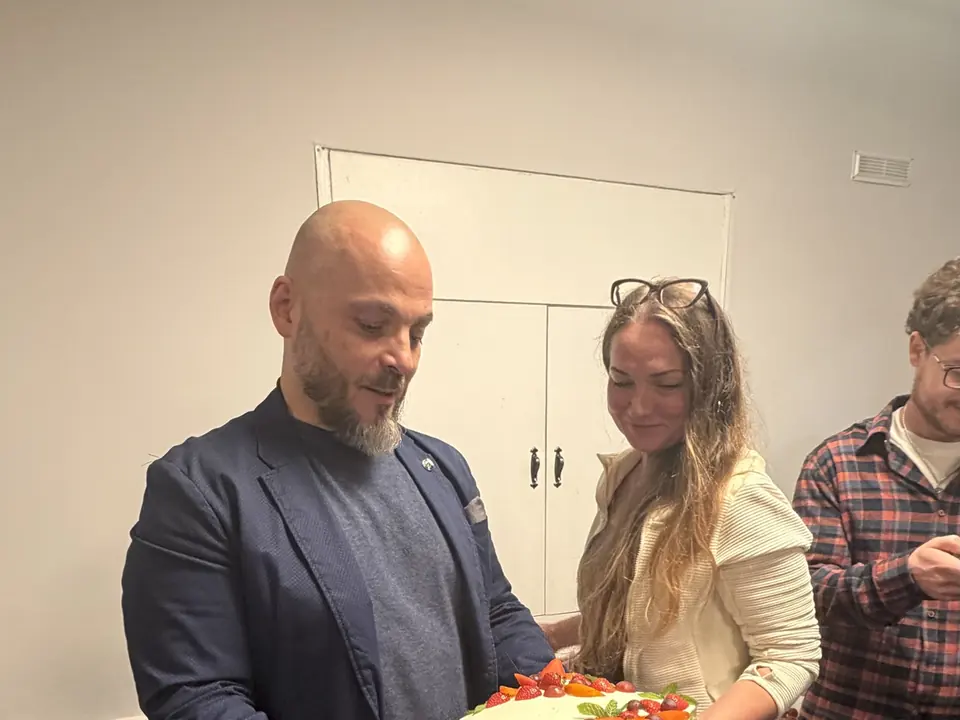 A guest holds a celebration cake, a club guest beside him